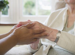 Close up of older woman and caretaker holding hands