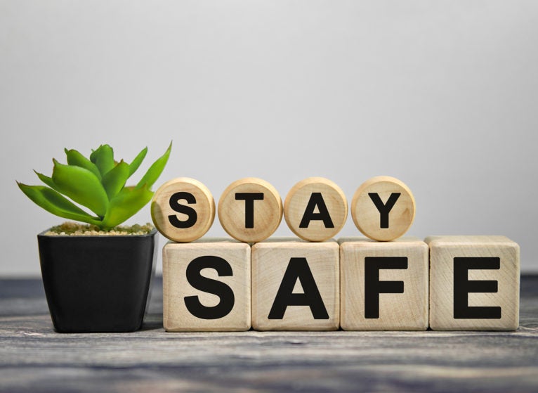 STAY SAFE - text on wooden cubes, green plant in black pot on a wooden background