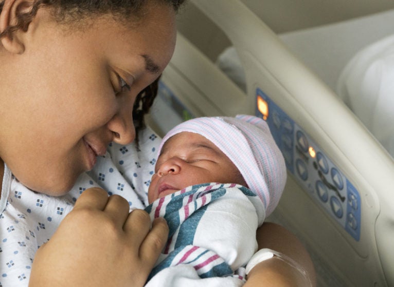 Black mother cradling newborn son in hospital