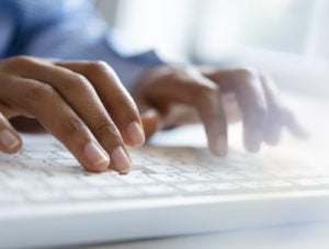 Hands of young woman typing on computer keyboard