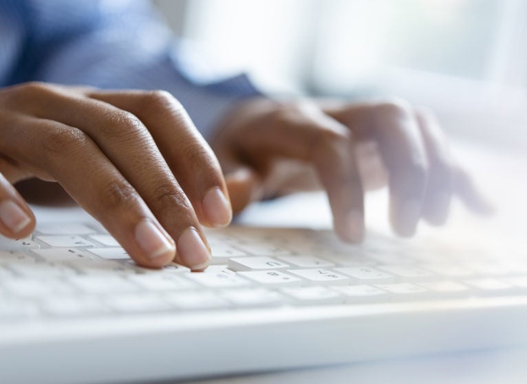 Hands of young woman typing on computer keyboard