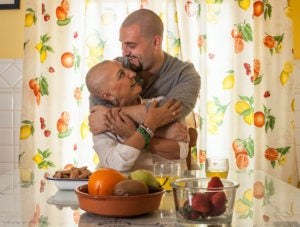 Fighting against breast cancer. Mature woman following a treatment against breast cancer, hugged by her son who, in solidarity, has shaved his hair.