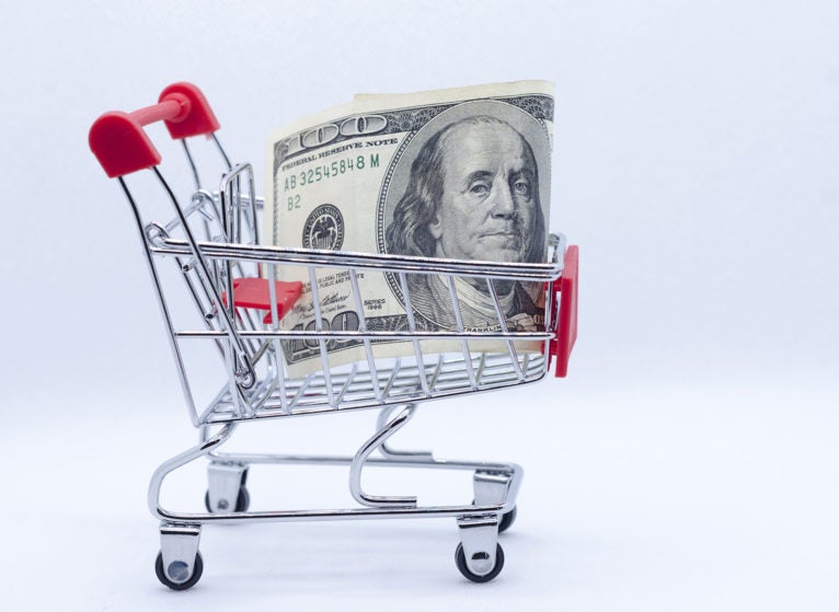 Shopping cart with 100 US dollars inside on white background