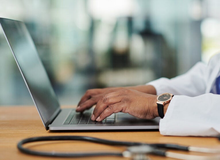 Closeup shot of an unrecognisable doctor using a laptop in her office