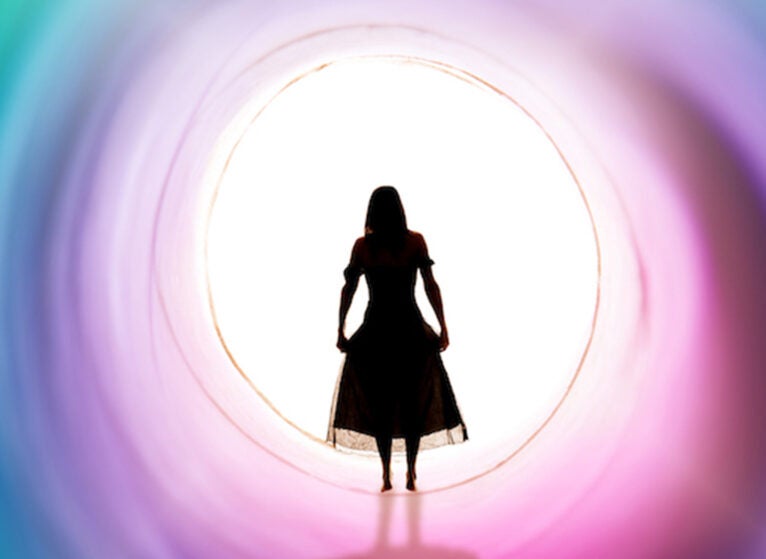 A conceptual image of the figure of a woman in a colorful tunnel about to step into the white light.