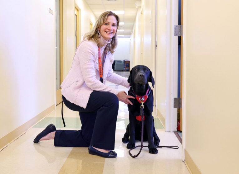 In addition to teaching, leading the Nursing School’s graduate program, and caring for patients, Beth Quatrara raises puppies like black lab Woody before they become service animals. Students say the dogs help them feel at home. (Photo by Matt Riley, University Communications)