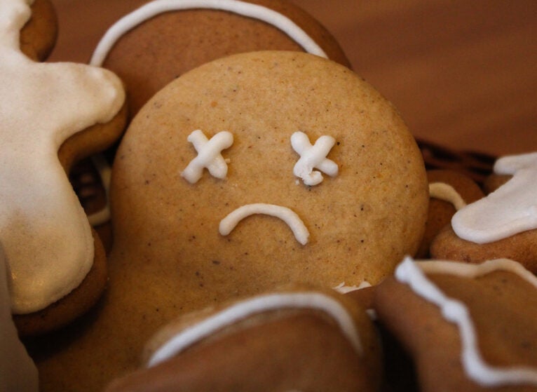 Homemade gingerbread men in the woven basket on the wooden table. Depressed christmas cookie with sad face covered with icing. New Year pastry in the shape of stars and men. Winter background
