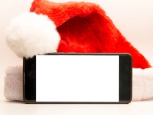 Mobile phone with blank screen in front of a Santa Claus hat