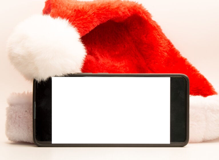 Mobile phone with blank screen in front of a Santa Claus hat