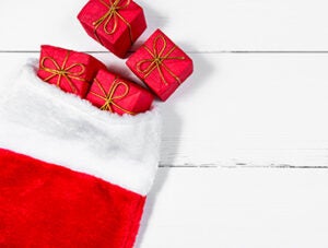 Christmas Stocking on White Wooden Table with Presents Rolling out, seen from directly above.