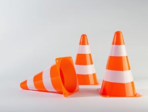 A traffic cone lying on its side next to two standing traffic cones