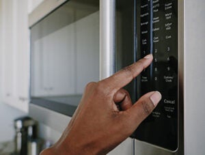 Close-up of unrecognizable black woman setting cook time on microwave