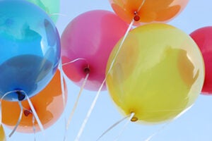 Colorful balloons flying in blue sky.