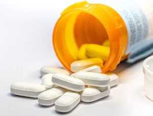 Close-up of pills spilling from bottle on white background