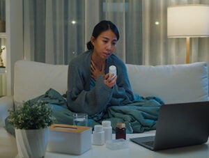 Young Asian girl patient consult doctor on laptop video call medicine dosage instruction on medical app in telemedicine online service in home at night. Quarantine at home, Social distance concept.