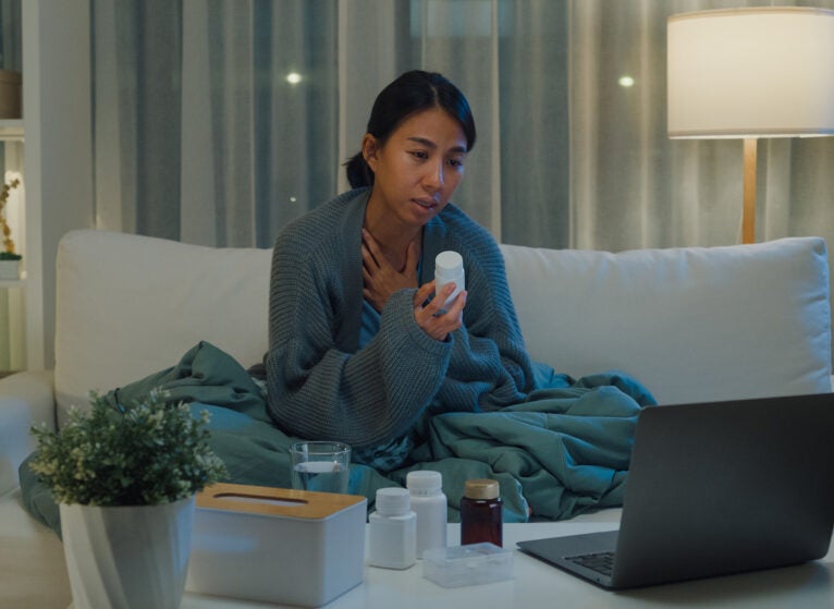 Young Asian girl patient consult doctor on laptop video call medicine dosage instruction on medical app in telemedicine online service in home at night. Quarantine at home, Social distance concept.