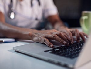 Close up of black female doctor using laptop.